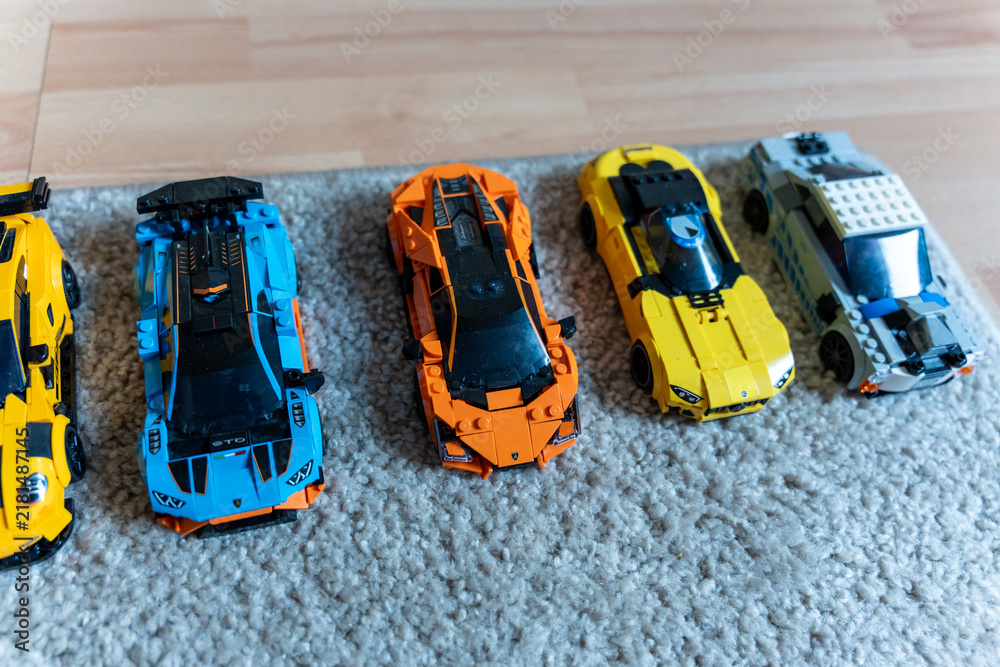 Obraz premium Warsaw, Poland - Sep 4, 2026: Row of five LEGO Technic model cars in yellow, orange and blue on a gray rug
