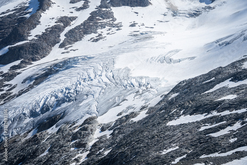 Konstfotografi Glacier icefall with deep crevasses flowing over rocky mountain terrain in Hohe