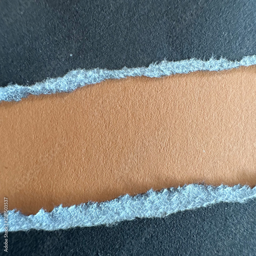 Torn black paper strip revealing a tan cardboard background