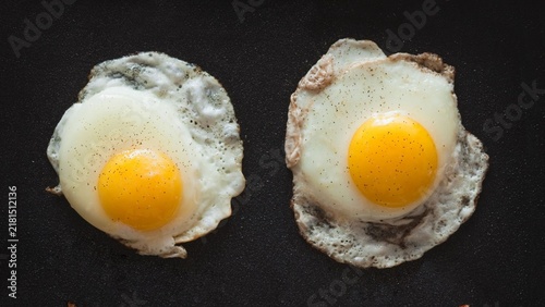 Quadro su tela Two sunny-side-up eggs sit on a dark pan