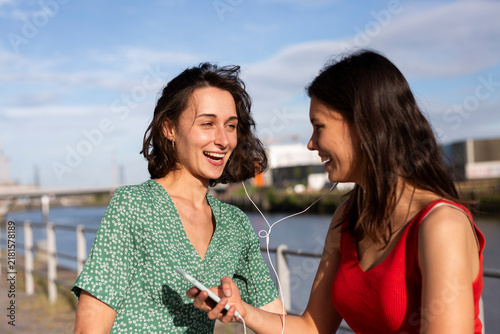 Female friends share an earphone and listen to music in Hamburg