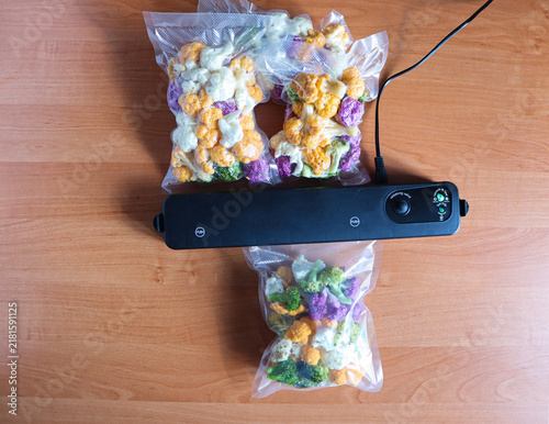 Colorful vegetables, cauliflower packed in bags with a vacuum sealer on a wooden table
