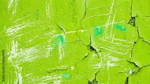 Bright lime green painted metal surface showing extensive weathered textures with peeling layers of chipped pigment and rustic industrial decay marks