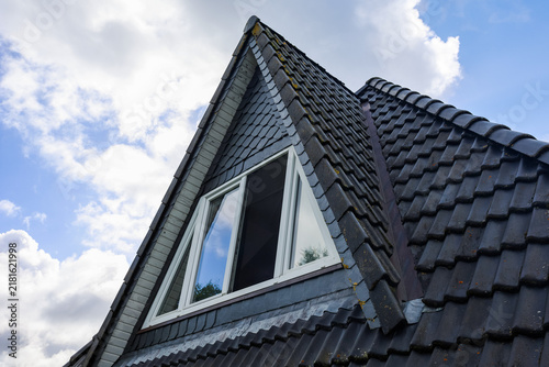 Building roof with dormer window under a blue sky