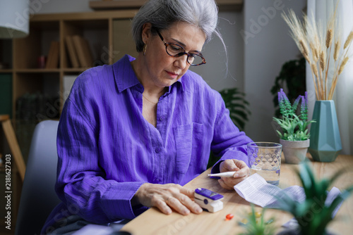 Woman using glucose monitor for diabetes self test at home