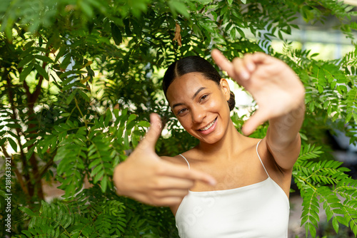 Smiling woman making finger frame gesture outdoors in nature