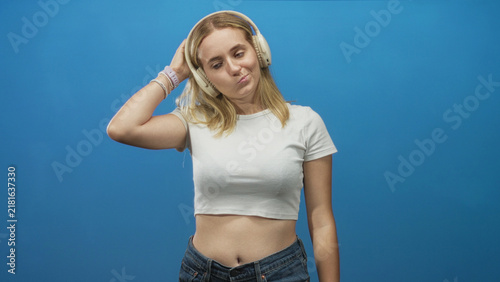 Foto Woman with headphones touching one earcup and shrugging, midriff exposed in studio; bemusement doubt