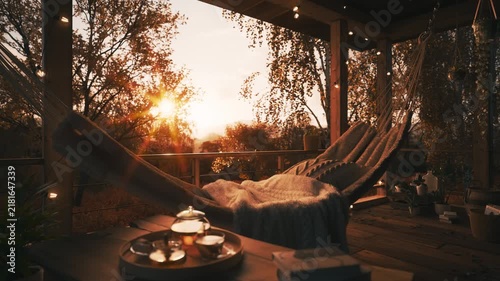 Cozy Autumn Terrace with Hammock and Tea at Golden Sunset. Golden autumn in a country house. Beautiful terrace in a private house