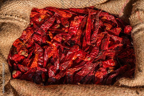 фотографія Long dried red chili peppers filling an open burlap sack