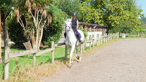 Foto Beautiful young girl on a white horse at an equestrian farm
