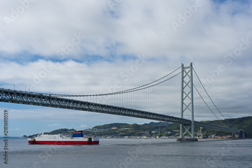 Passenger and vehicle ferry sails under suspension bridge off coast of Awaji Island