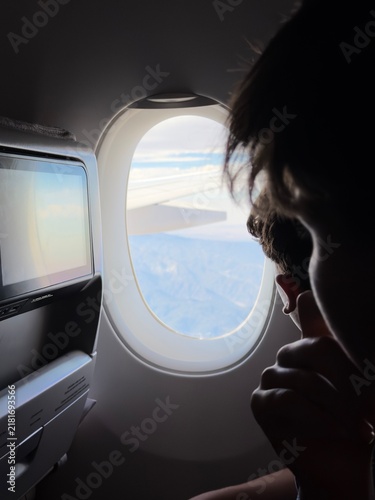 Foto Passenger looking at clouds and sky from aircraft window view with entertainment