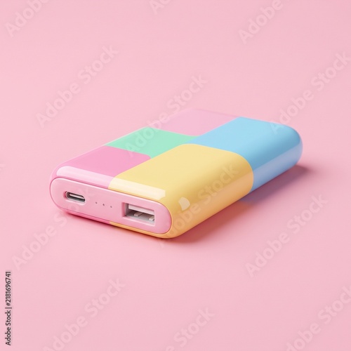 A small portable power bank with colorful pastel blocks isolated on a soft pink background