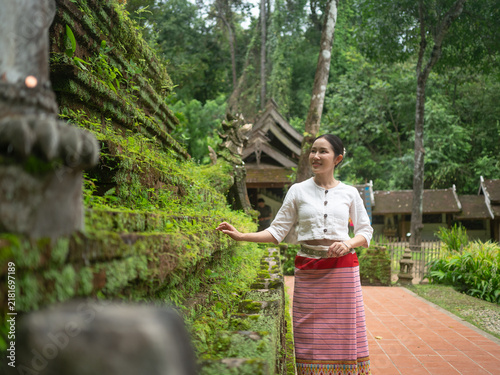 Fotografía Asian woman in traditional Thai dress standing near mossy ancient pagoda in temp
