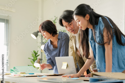 Foto Team leaning over desk discussing strategy chart together, one colleague laughin
