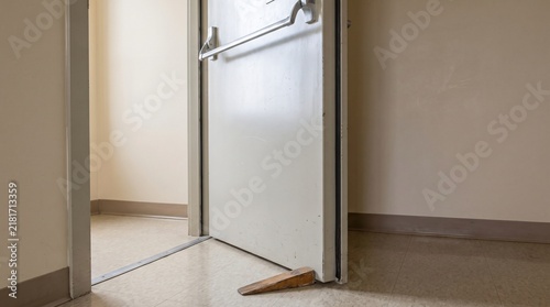 Fire Safety Breach Concept, Fire Door Wedged Open In A Plain Institutional Corridor