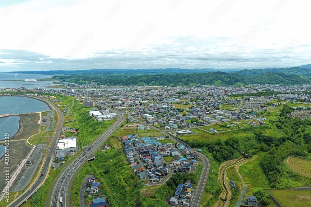 Obraz premium Aerial drone photo of coastal town with wind turbines and harbor in Rumoi, Hokkaido, Japan