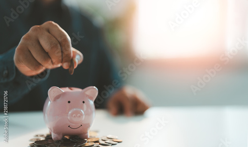 Hand putting coins into a pink piggy bank saving bank for account save money. Planning step up, saving money for future plan, retirement fund. Business investment-finance accounting concept.