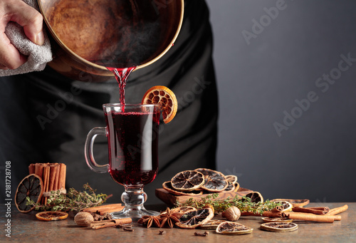 Konstfotografi Mulled wine is poured from a old brass pan into a glass mug.