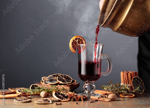 Cuadro en lienzo Mulled wine is poured from a old brass pan into a glass mug.