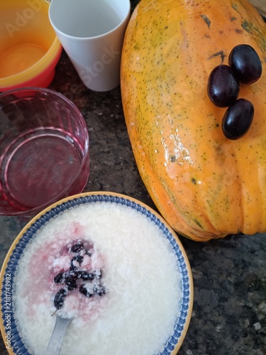 Healthy breakfast still life with bowl of yogurt, fresh grapes, whole papaya, and colorful bowls – photo for recipe websites, healthy lifestyle blogs and nutrition magazine illustrations.