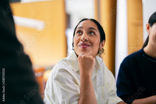 Thoughtful Young Woman Smiling During Office Team Meeting