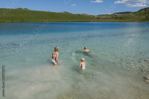 Woman and children are swimming in a mountain lake