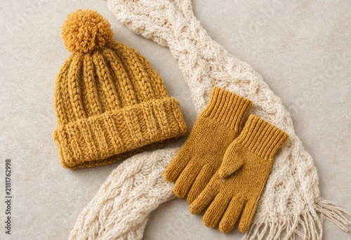 Warm knit winter hat and gloves with textured scarf on neutral background