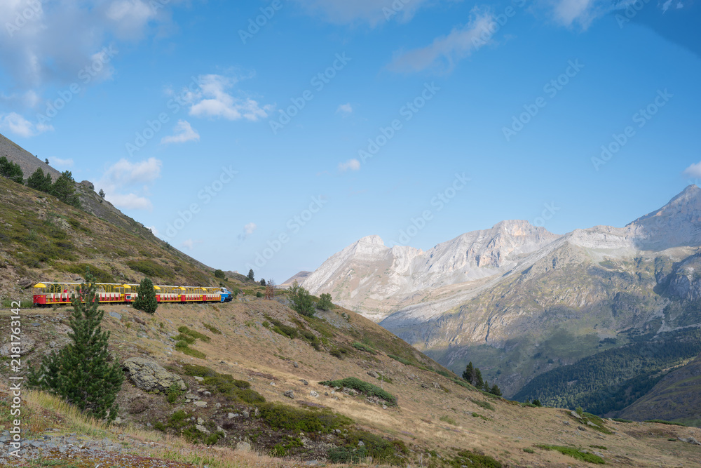 Fototapeta premium Petit Train d'Artouste moving through majestic Pyrenees mountain landscape under clear blue sky in France