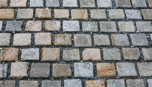 Obraz na plátně Closeup view of cobblestone pavement ground texture with square stone blocks in pattern