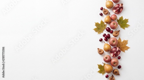 A beautiful vertical border composition featuring fresh seasonal fruits and colorful autumn leaves on a clean white background perfect for a festive thanksgiving holiday celebration