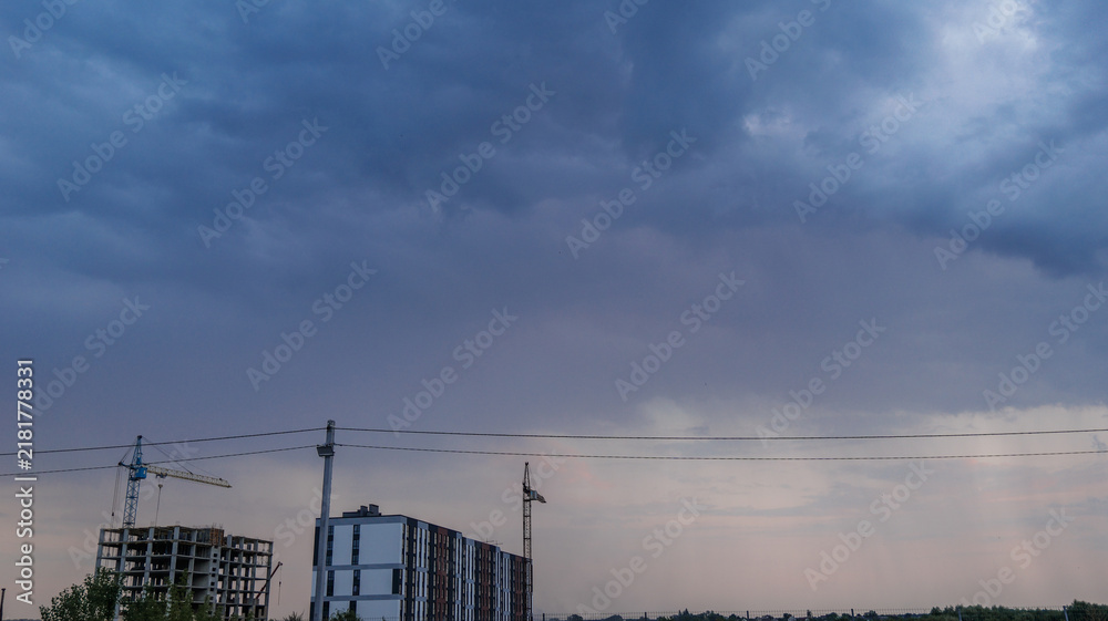 Fototapeta premium Construction site with cranes under a dramatic cloudy sky at dusk