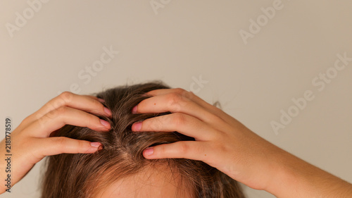 Woman's hands gently touching her scalp and hair, close-up view