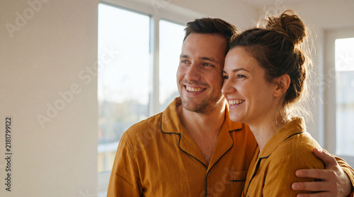 Happy young couple hugging in their bright home with copy space. 
