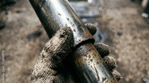 mechanic holding worn rusty shock absorber | car suspension repair and maintenance | close up of dirty work gloves in garage | industrial automotive metal pipe part replacement