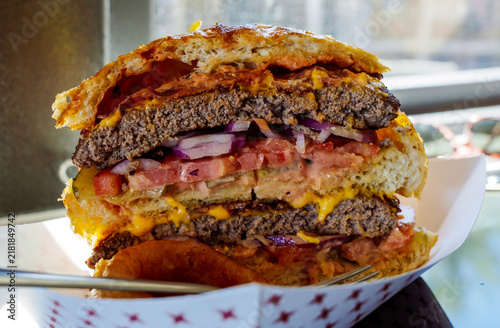 Giant double Cheeseburger cut in half with cheese, onions, tomatoes and lettuce
