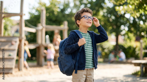 Happy little school boy with backpack walking in sunny outdoor playground perfect for childhood education and active learning environment