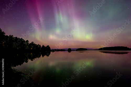 Northern lights dancing over lake in Farnebofjarden national park in north of sweden