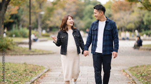 Obraz na płótnie 秋の公園を手をつないで笑顔で散歩する妊婦と夫の夫婦