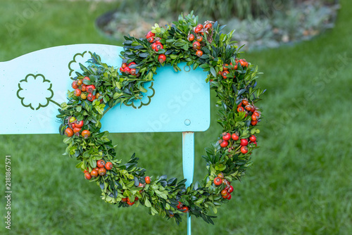 Kranz in Herzfporm aus Buchs und Hagebutten am Gartenstuhl	
