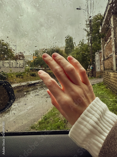 Hand on rainy car window