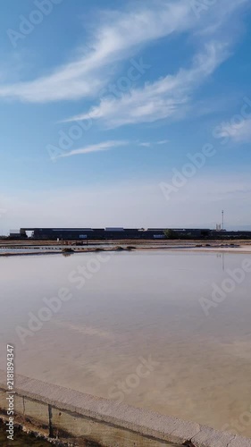 Panoramic scenic view of the historic salt pans and wetlands at Solana Nin in Croatia. Evaporation basins, concrete pathways, and lush aquatic vegetation under a clear blue sunny sky in Dalmatia.