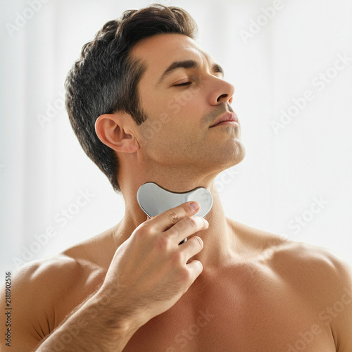 Man Using a Gua Sha Facial Massage Tool for Skincare and Self Care