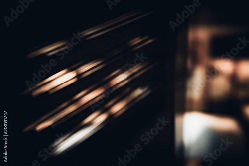 Bild auf Leinwand Dark abstract photograph created with intentional camera movement, featuring diagonal warm light streaks, blurred geometric forms and ample negative space
