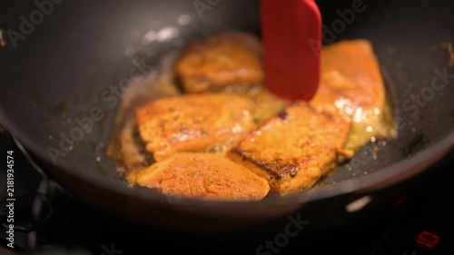 The red boneless marinated salmon fish is fried with oil. 4K video of Fish Fry in a black pan. Copyspace.