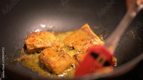 The red boneless marinated salmon fish is fried with oil. 4K video of Fish Fry in a black pan. Copyspace.
