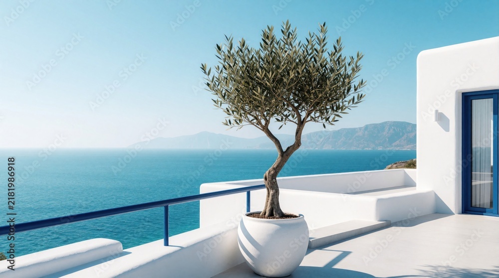 Obraz premium Modern white terrace overlooks blue Mediterranean sea, distant mountains. Small olive tree grows in large ceramic pot on sunny balcony. Scenic coastal view with clear sky, peaceful summer vibes in