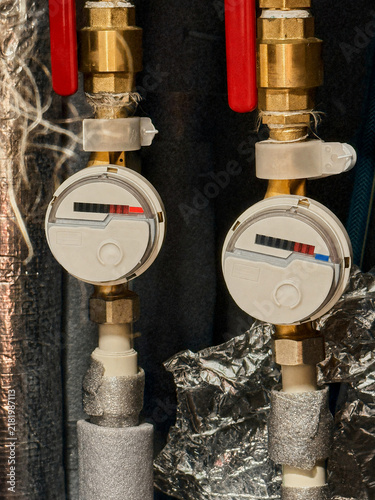 Water meters installed on pipes with insulation and valves visible
