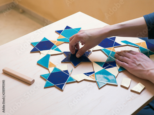 Photorealistic hands arranging colorful mosaic tiles into stars