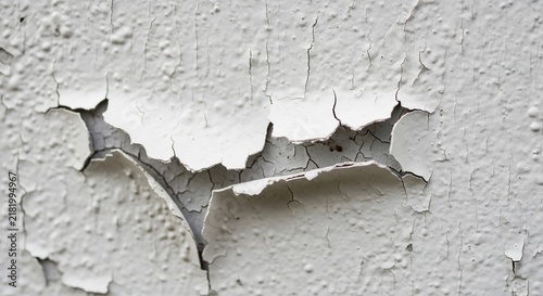 White painted wall surface showing heavy cracks and peeling texture from aging and weather damage.